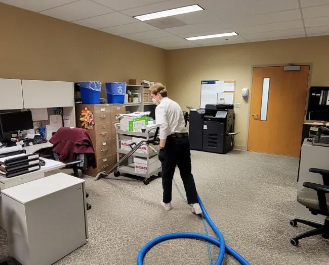Prestige Carpet Cleaning technician in Oshawa office with vacuum hose